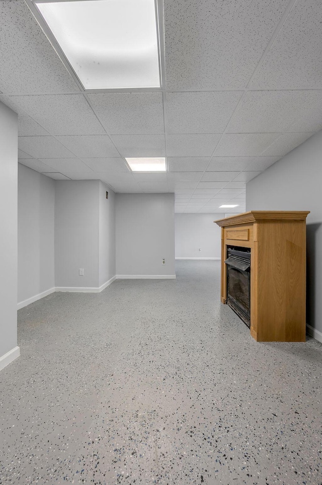 finished below grade area featuring baseboards, a paneled ceiling, and a fireplace