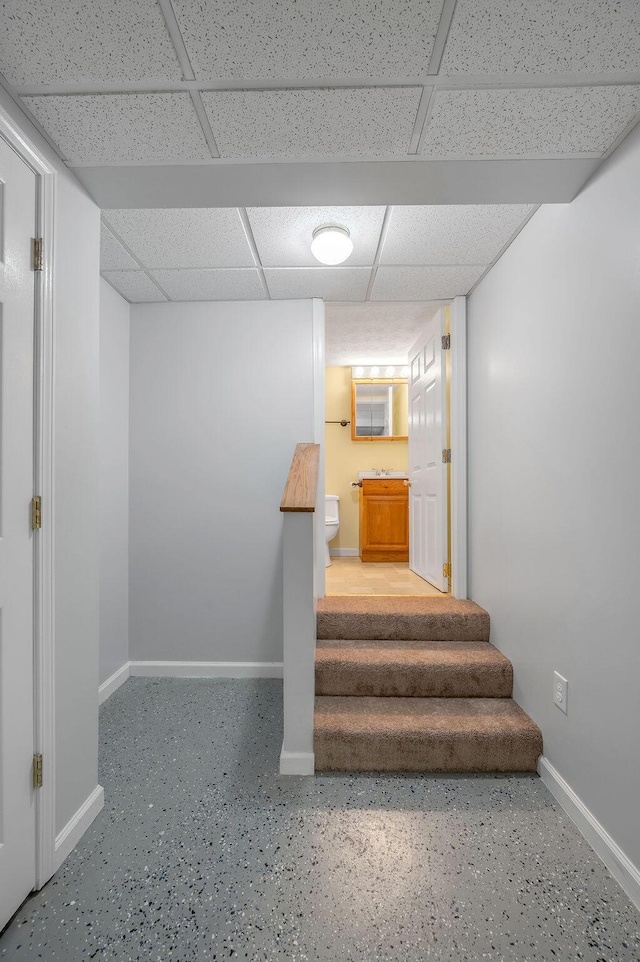 stairway with a drop ceiling and baseboards