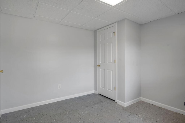 unfurnished room with a paneled ceiling, baseboards, and concrete flooring