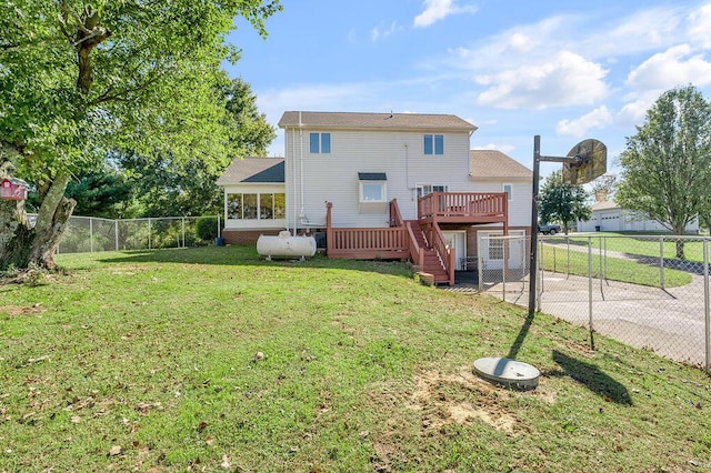 back of house featuring a fenced backyard, a lawn, a deck, and a sunroom