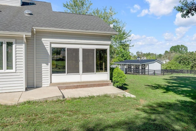 back of property featuring a lawn, a sunroom, roof with shingles, and fence