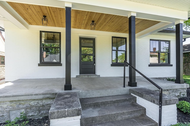 property entrance with brick siding and a porch