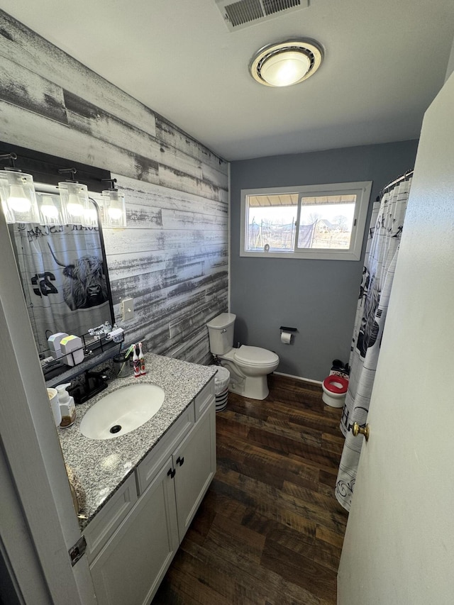 full bathroom with vanity, wood finished floors, visible vents, baseboards, and toilet