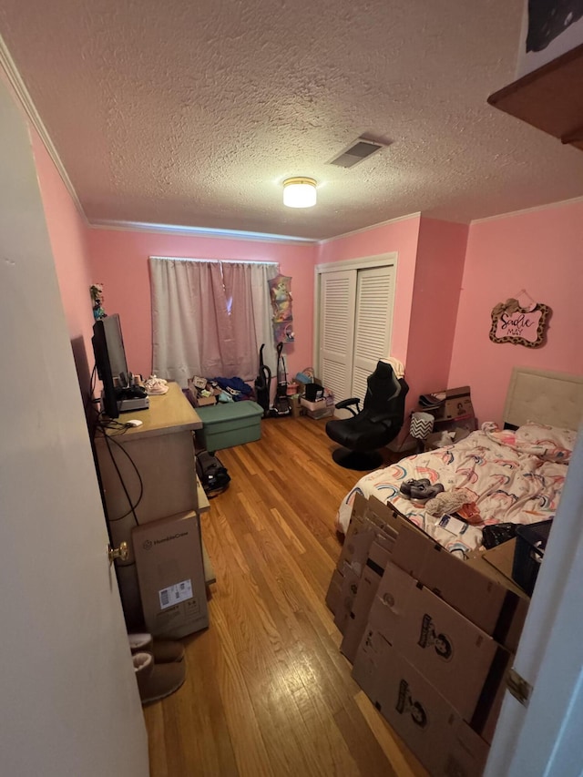 bedroom with visible vents, a textured ceiling, a closet, and light wood finished floors