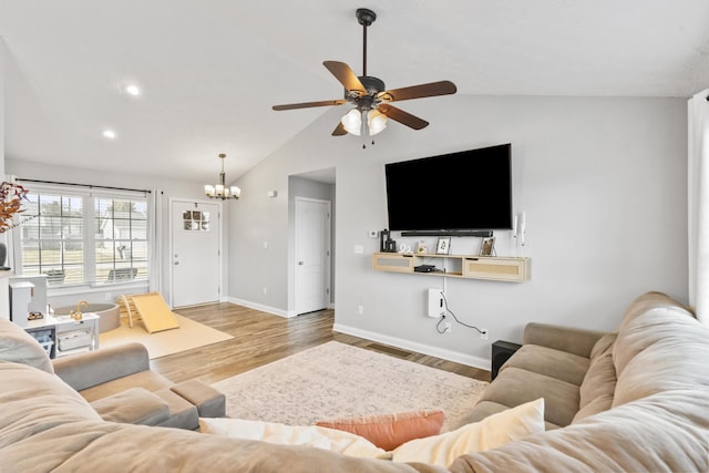 living area featuring baseboards, ceiling fan with notable chandelier, wood finished floors, and vaulted ceiling