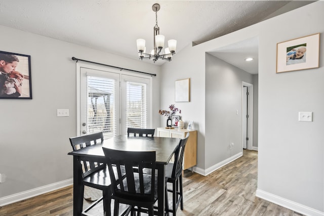 dining area featuring an inviting chandelier, baseboards, and light wood finished floors