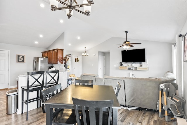 dining area with light wood finished floors, recessed lighting, ceiling fan with notable chandelier, and vaulted ceiling