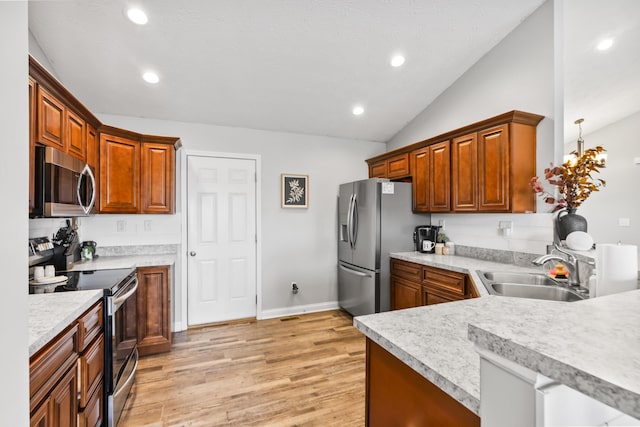 kitchen with light wood-type flooring, light countertops, vaulted ceiling, appliances with stainless steel finishes, and a sink