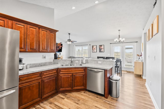 kitchen with a wealth of natural light, appliances with stainless steel finishes, a peninsula, and a sink