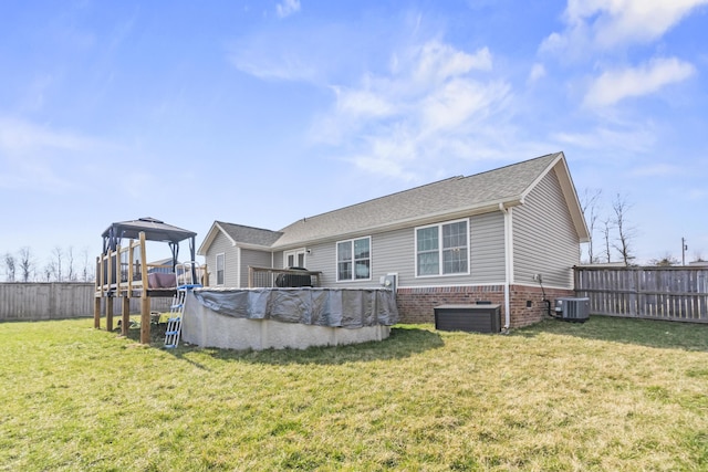 back of property featuring fence, cooling unit, a fenced in pool, and a lawn