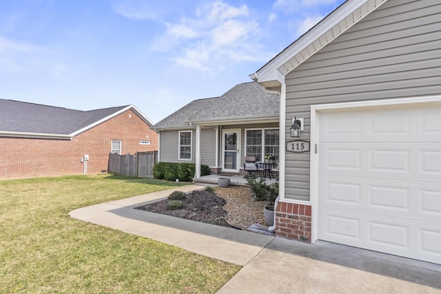 doorway to property featuring a yard, roof with shingles, an attached garage, and fence