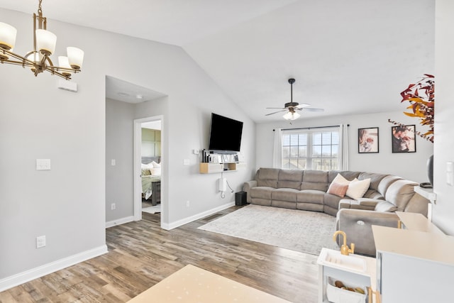 living room with visible vents, lofted ceiling, ceiling fan with notable chandelier, wood finished floors, and baseboards