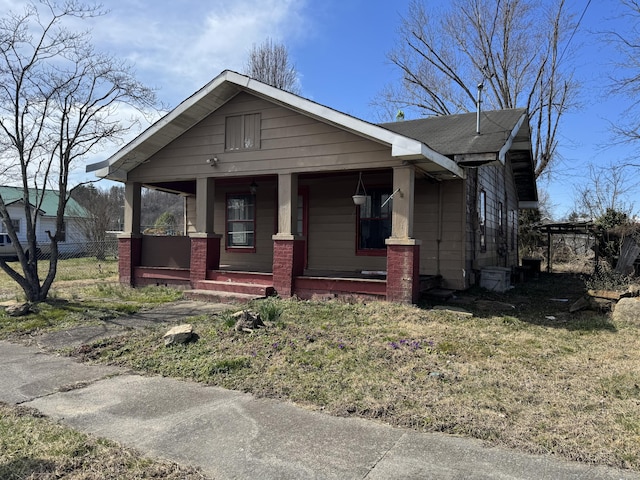 view of front of home featuring covered porch, roof with shingles, and fence