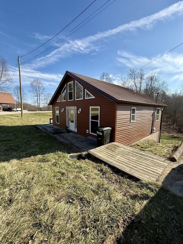 rear view of property featuring a lawn and metal roof