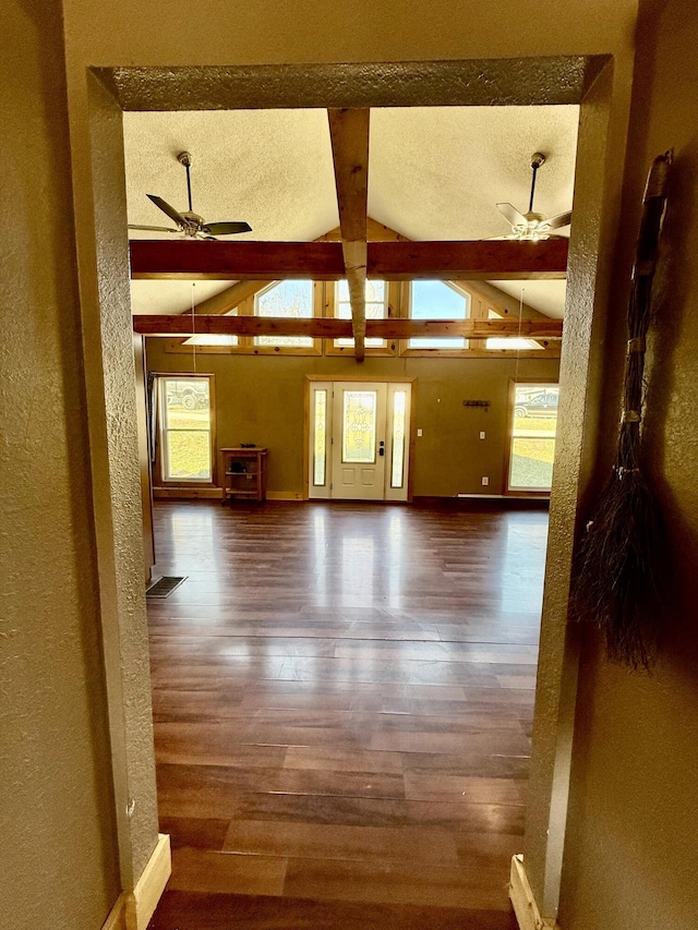 interior space with lofted ceiling with beams, wood finished floors, a textured wall, and ceiling fan