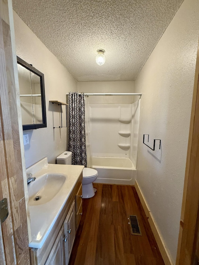 bathroom featuring visible vents, toilet, vanity, wood finished floors, and a textured ceiling