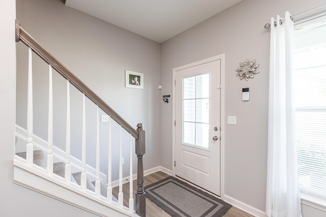 entryway with plenty of natural light, stairs, and wood finished floors