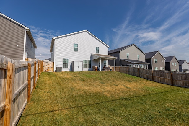 back of property featuring central air condition unit, a yard, a fenced backyard, and a residential view