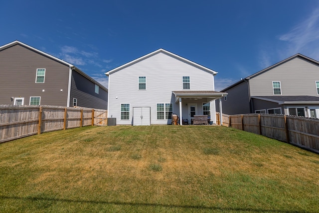 rear view of property with central air condition unit, a yard, and a fenced backyard