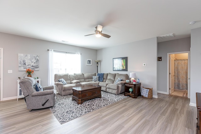 living area featuring light wood finished floors, visible vents, a ceiling fan, and baseboards