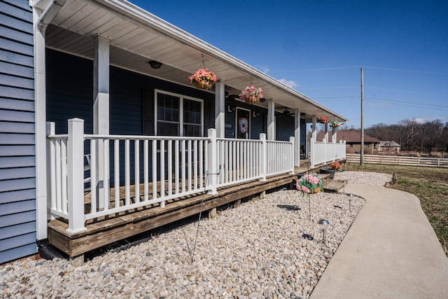 doorway to property featuring covered porch and fence