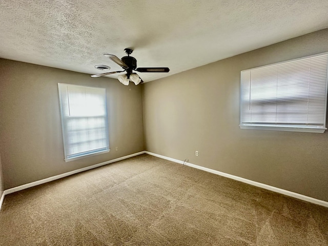 empty room with carpet flooring, visible vents, baseboards, and ceiling fan