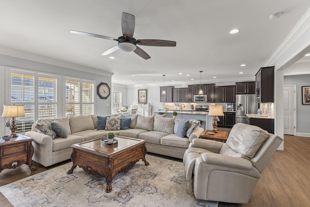 living area featuring recessed lighting, light wood-style floors, crown molding, baseboards, and ceiling fan