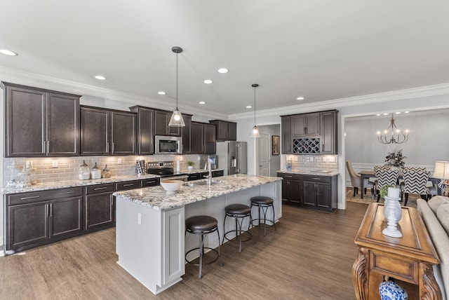 kitchen with dark brown cabinetry, pendant lighting, a breakfast bar area, wood finished floors, and stainless steel appliances