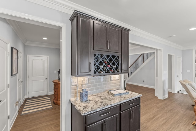 bar featuring ornamental molding, wood finished floors, recessed lighting, a bar, and baseboards