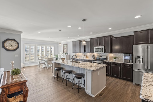 kitchen featuring backsplash, appliances with stainless steel finishes, a kitchen breakfast bar, and dark wood-style flooring