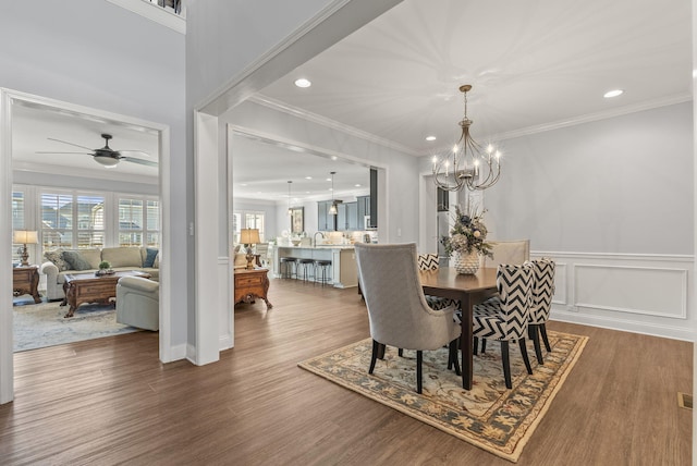 dining space featuring crown molding, wood finished floors, and a wainscoted wall