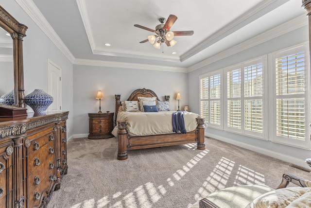 carpeted bedroom featuring a tray ceiling, crown molding, baseboards, and ceiling fan