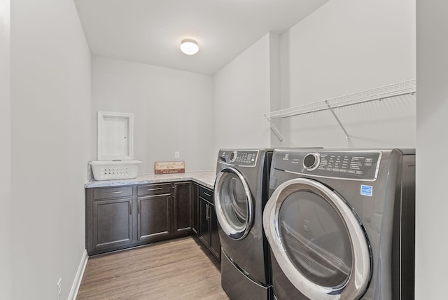 laundry area with baseboards, cabinet space, light wood-style floors, and independent washer and dryer