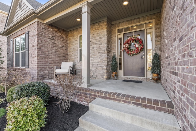 entrance to property with a porch and brick siding