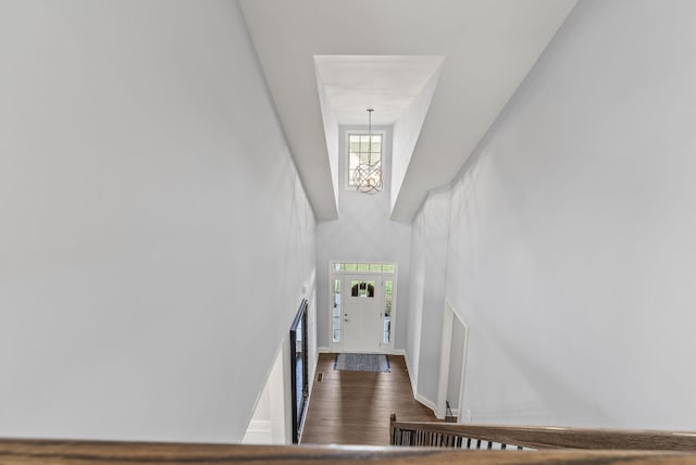 stairway with wood finished floors, plenty of natural light, an inviting chandelier, and a towering ceiling