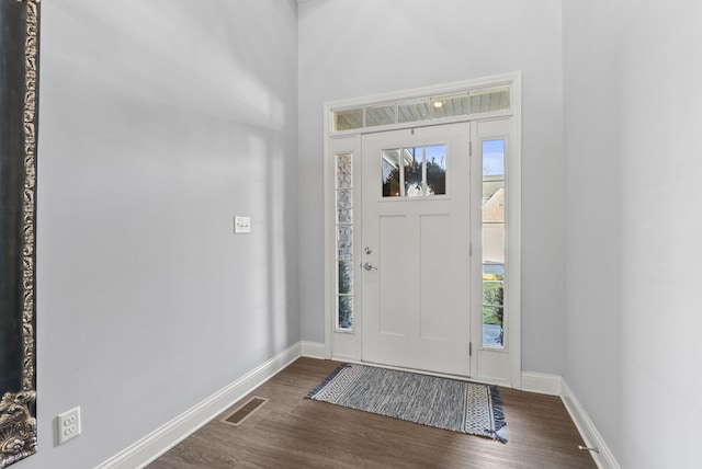 foyer entrance with dark wood-type flooring, baseboards, and visible vents