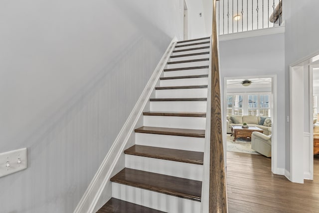 staircase featuring wood finished floors and a towering ceiling