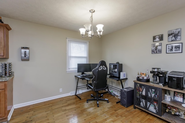 office space featuring light wood-style flooring, an inviting chandelier, and baseboards