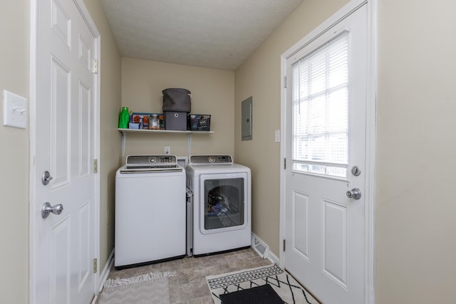 clothes washing area with baseboards, washer and clothes dryer, electric panel, laundry area, and a textured ceiling