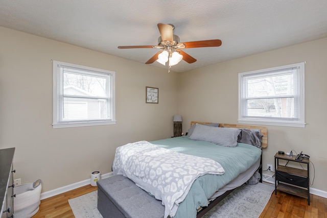 bedroom featuring multiple windows, baseboards, and wood finished floors