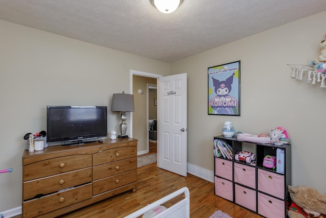 bedroom featuring wood finished floors, baseboards, and a textured ceiling