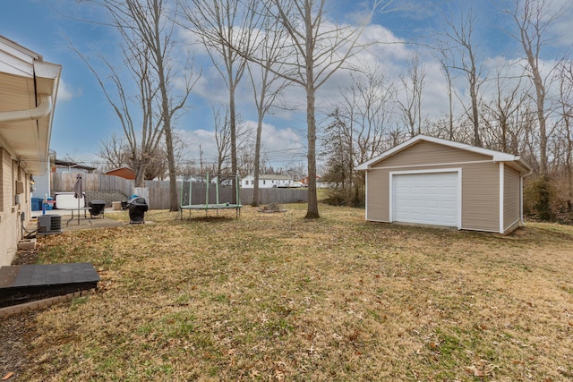 view of yard featuring a trampoline, central AC, fence, an outdoor structure, and a garage