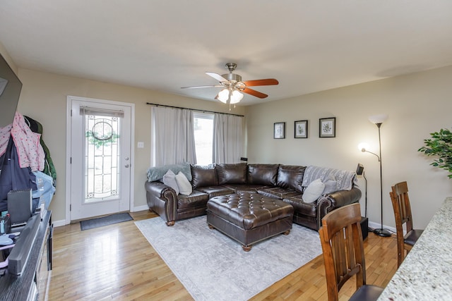 living area with baseboards, light wood-type flooring, and a wealth of natural light