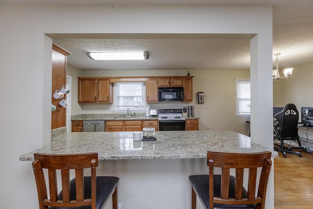 kitchen featuring black microwave, dishwasher, range with electric stovetop, a peninsula, and a sink