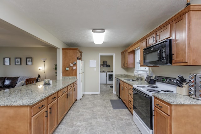 kitchen featuring washing machine and dryer, light stone counters, brown cabinetry, white appliances, and a sink