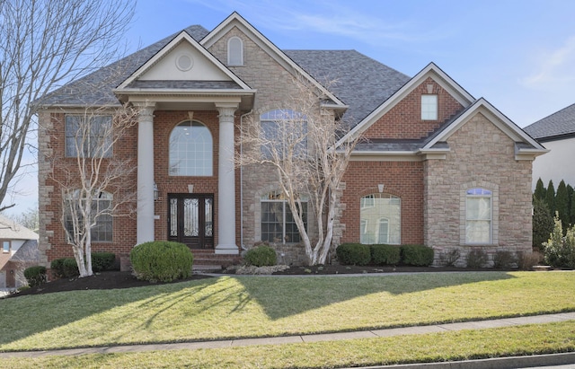 view of front of property featuring a front lawn, brick siding, stone siding, and a shingled roof