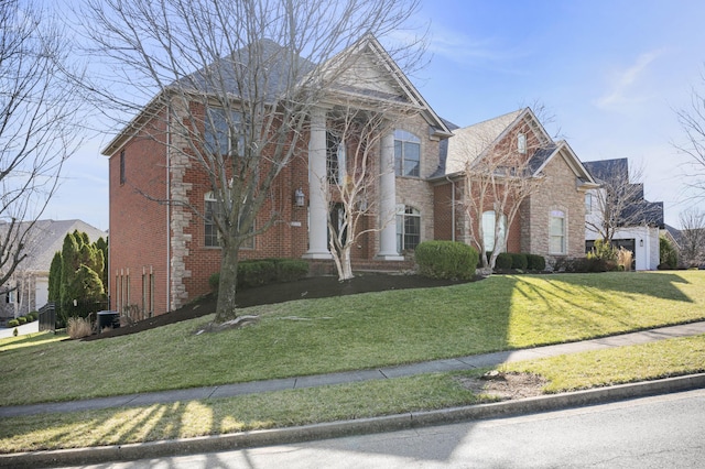 neoclassical home with brick siding and a front yard