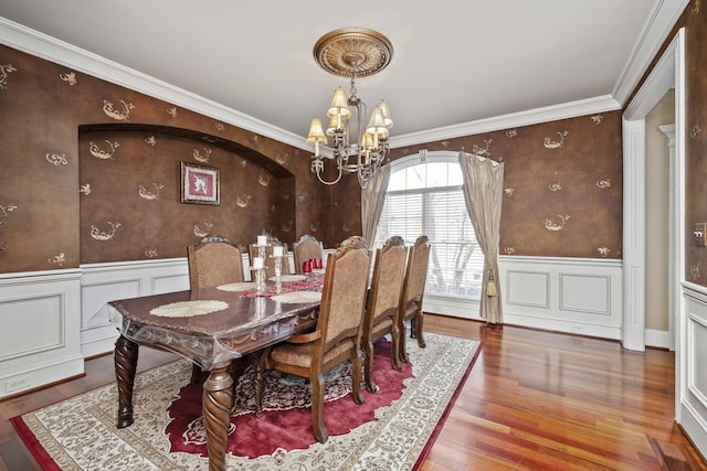 dining room featuring a chandelier, a wainscoted wall, ornamental molding, and wood finished floors