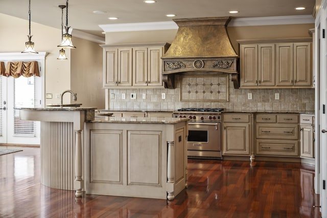 kitchen with cream cabinetry, a center island with sink, light stone counters, luxury stove, and custom exhaust hood