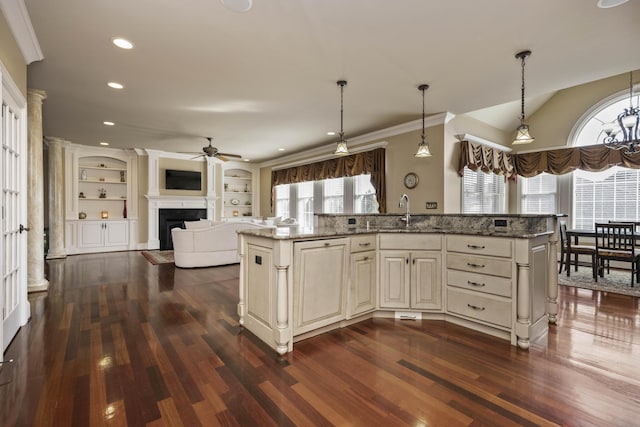 kitchen with light stone counters, a fireplace, dark wood-style flooring, and a sink